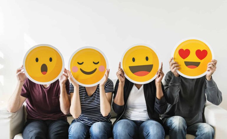 four people hold happy emoji masks